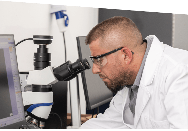Arab Basalt Fiber Company worker wearing protective glasses and work uniform, inspecting materials under a microscope